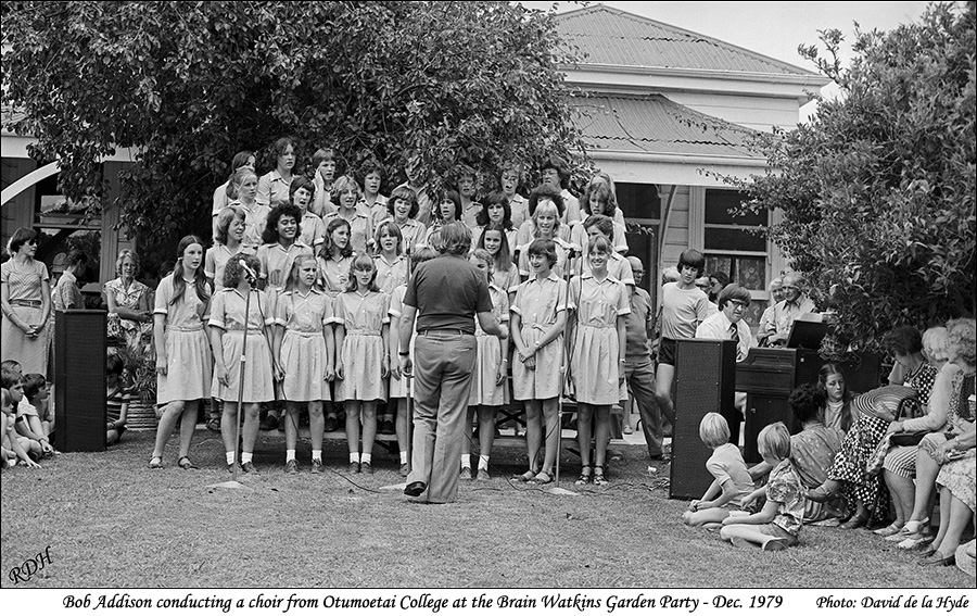 Bob Addison conducting a choir from Otumoetai College at Brain Watkins Garden Party - Dec. 1979