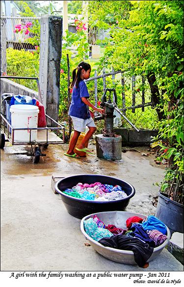 A girl doing the family washing at a public water pump