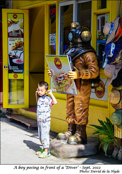 A boy posing in front of a diving suit - D'mall