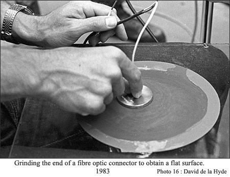 Grinding the end of a fibre optic connector to obtain a flat surface.
