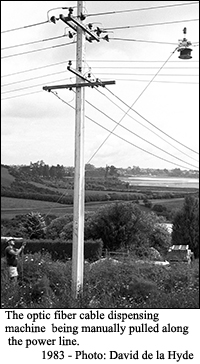 The fiber optic cable dispensing machine being manually pulled along a power line.